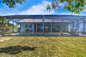 A house with a covered patio, a swimming pool, and a lawn. - Cozy Family Home in Punta Gorda, 5938 (Charlotte County)