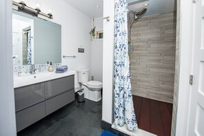 A modern bathroom with a grey vanity, a white toilet, and a shower with a blue floral shower curtain.