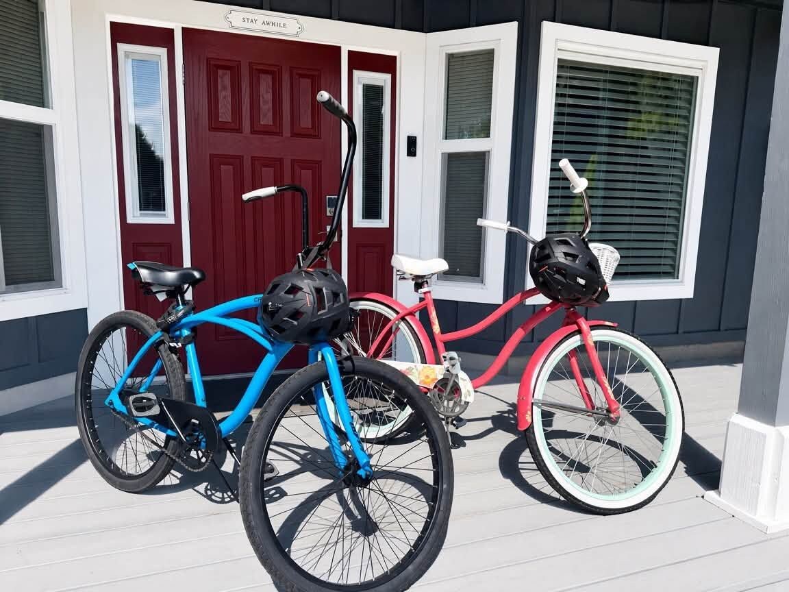 Two bicycles parked in front of a house with a red door and white shutters.