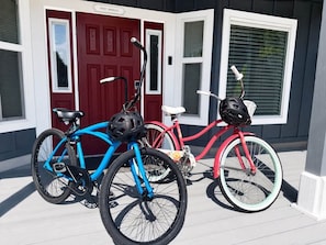 Deux vélos sont garés devant une maison avec une porte rouge et des volets blancs.