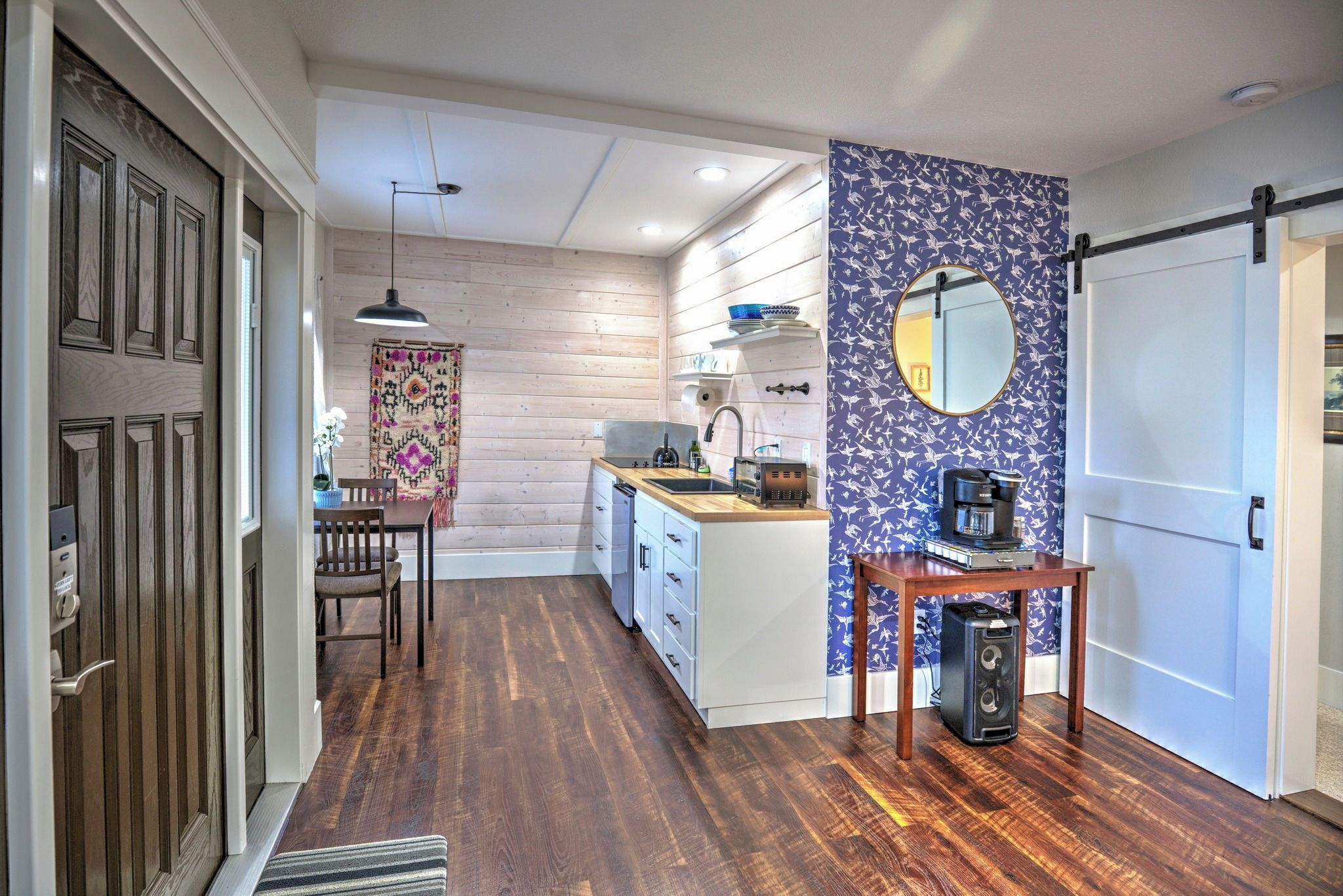 A modern kitchen with wooden flooring, a dining area with a table and chairs, and a kitchen counter with appliances.