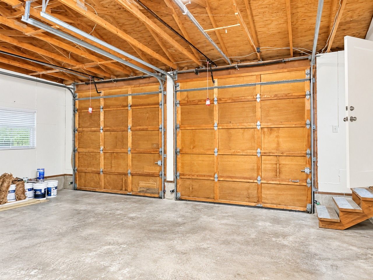 A spacious garage with wooden doors and a concrete floor.