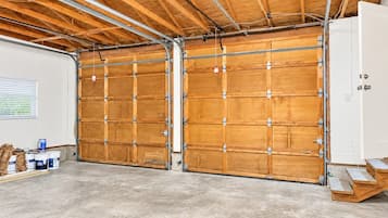 A spacious garage with wooden doors and a concrete floor.