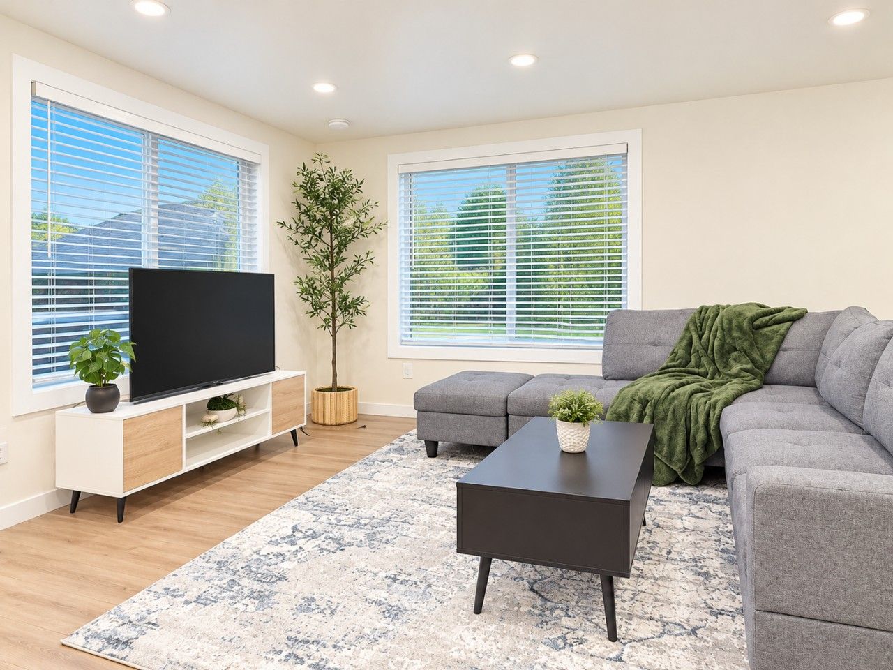 A modern living room with a flat-screen TV, grey sofa, and a coffee table.