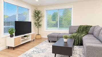 A modern living room with a flat-screen TV, grey sofa, and a coffee table.