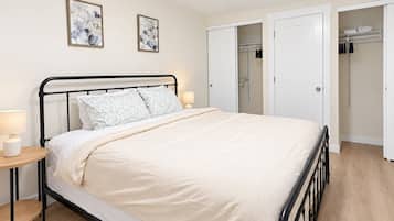 A bedroom with a bed, bedside tables, a wardrobe, and two wall-mounted paintings.