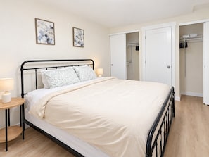 A bedroom with a bed, bedside tables, a wardrobe, and two wall-mounted paintings.