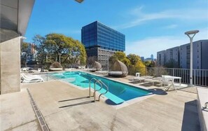 A rooftop pool with lounge chairs and a view of a modern building. - Midtown Atlanta 2 bedroom luxury condo (Atlanta)