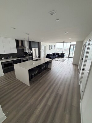 A modern kitchen with a central island, bar stools, and a dining area with a view. - Midtown Atlanta 2 bedroom luxury condo (Atlanta)