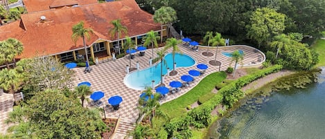 A resort with a swimming pool, lounge chairs, and a dock.