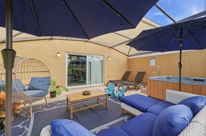 Ein Außenbereich mit Sitzgelegenheiten, einem Whirlpool, Liegestühlen und Sonnenschirmen.
