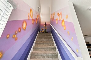 Eine Treppe mit einer Wand, die abstrakte Muster zeigt, und einem kleinen dekorativen Element oben.