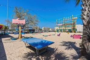 A beach with a table tennis table labeled 'BUTTERFLY,' a playground, and a sign that reads 'EQUINOPEAL of fun for you.' - Ocean Dunes Tower I | Ocean View | Pool | Sleeps 6 (Myrtle Beach)