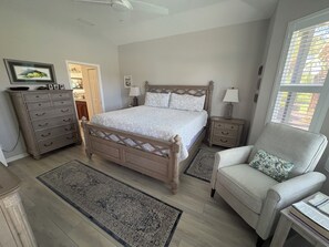 A bedroom with a bed, dresser, nightstands, chair, and a window with blinds. - Luxury pool home in the Venetian Golf and River Club (North Venice)