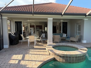 A covered patio area with a pool, outdoor furniture, and a view into the house. - Luxury pool home in the Venetian Golf and River Club (North Venice)