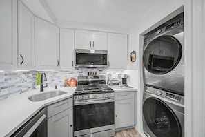 A compact kitchen with a microwave, stove, oven, and built-in dishwasher. - Mountain Creek Ski Condo | 3BR, Arcade, Mtn Views (Vernon Township)