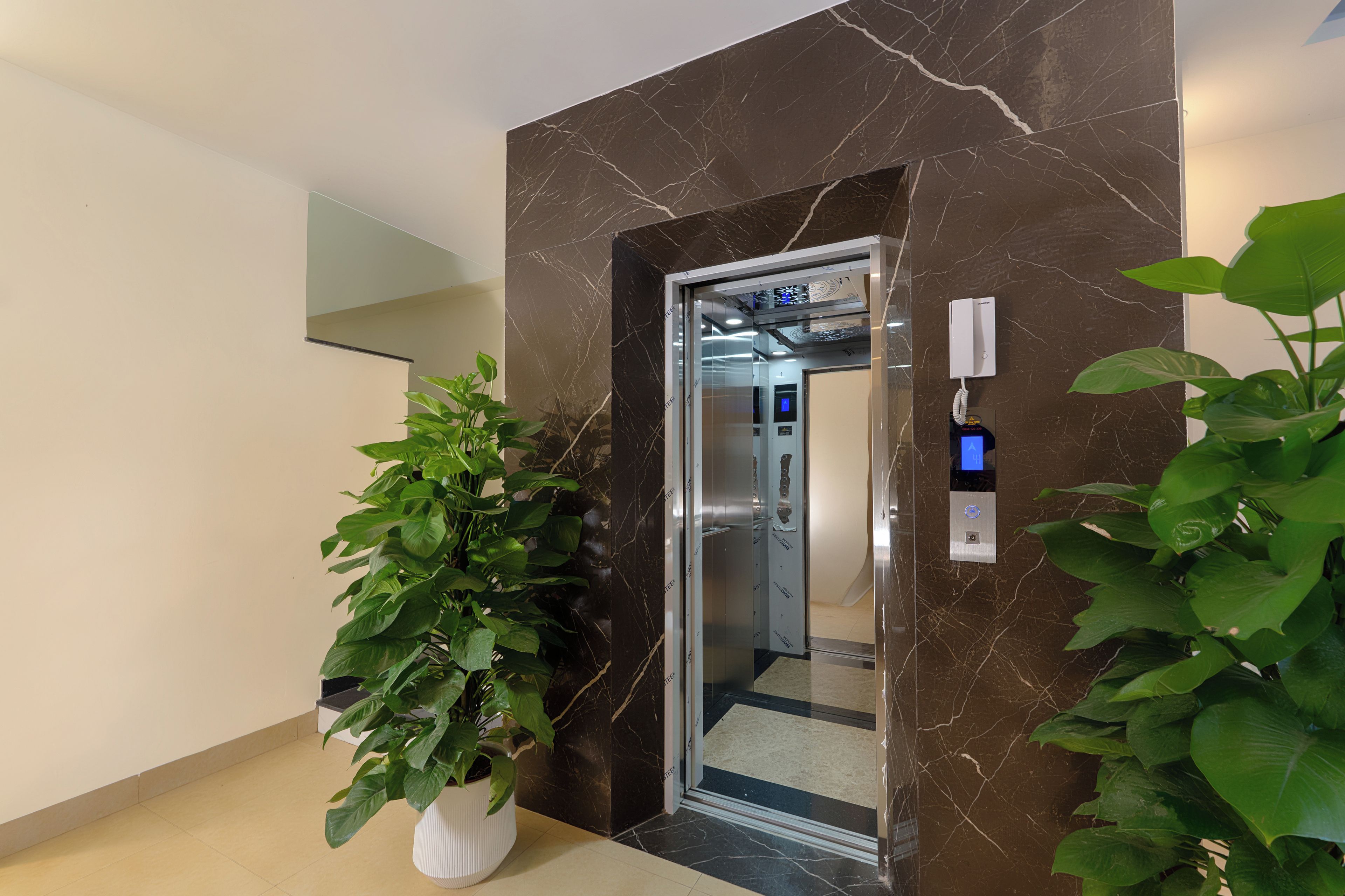 An elevator with a digital display, a phone, and a wall-mounted intercom.
