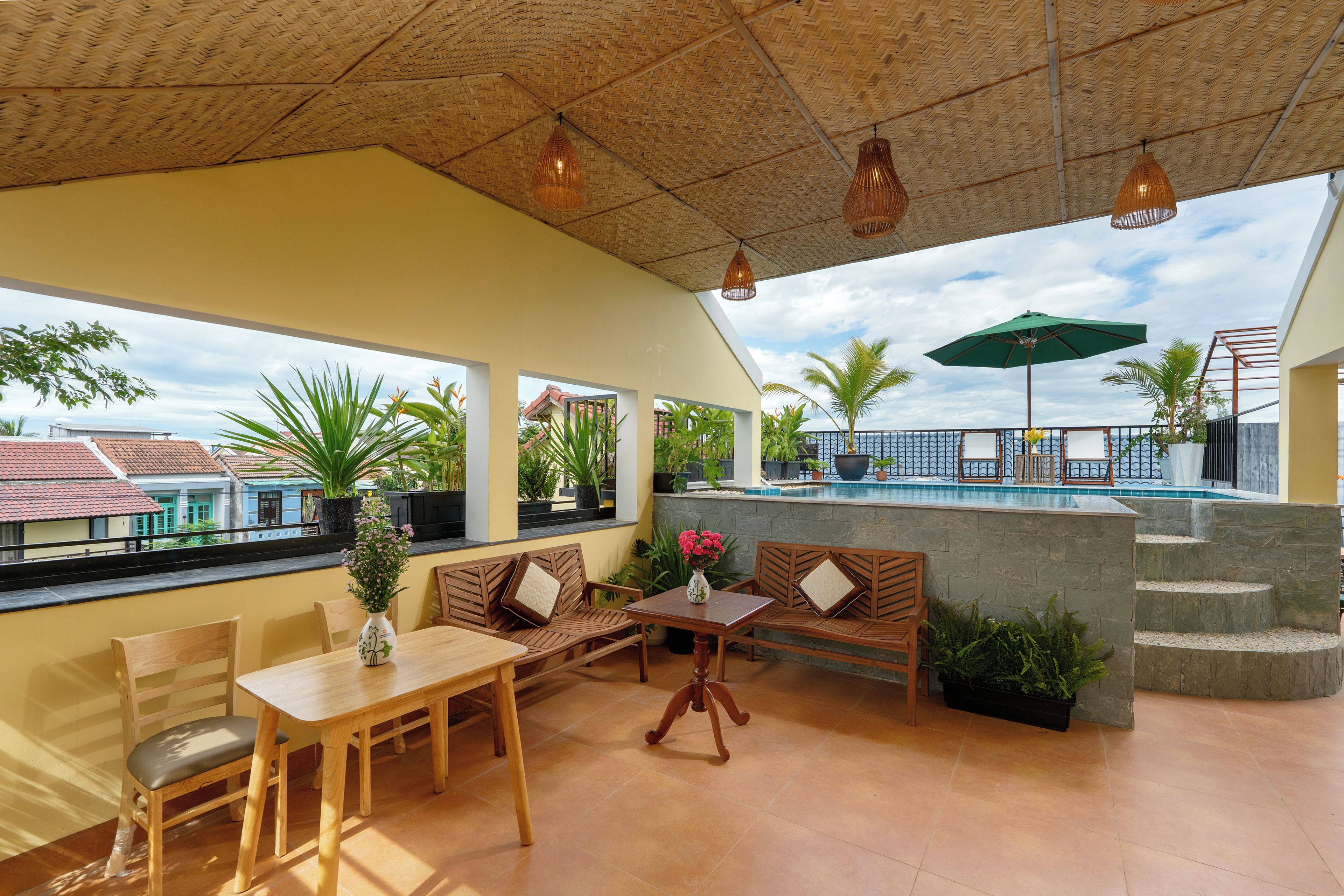 A terrace with a pool, wooden furniture, and potted plants.