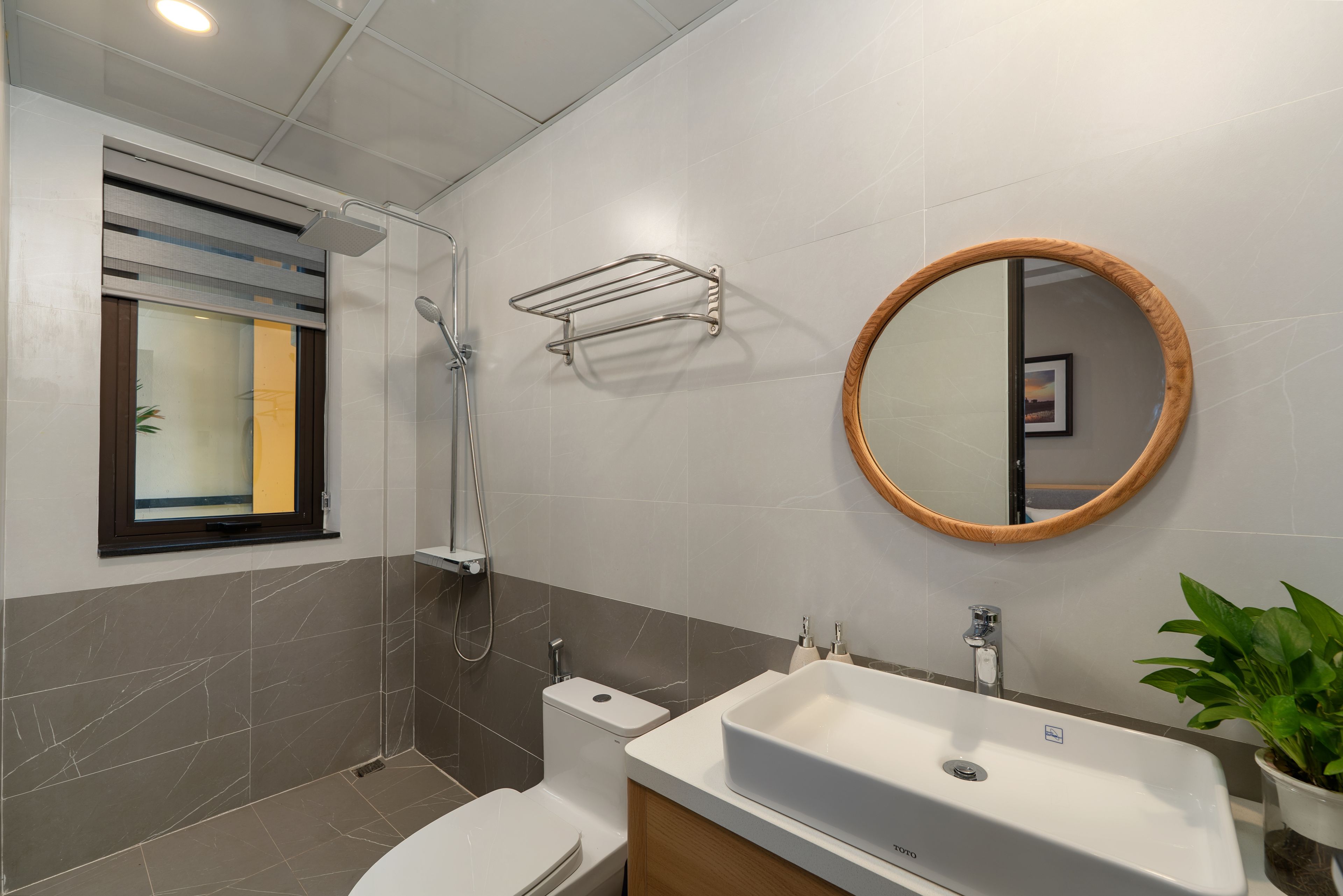 A modern bathroom with a shower, toilet, sink, and a mirror with a wooden frame.