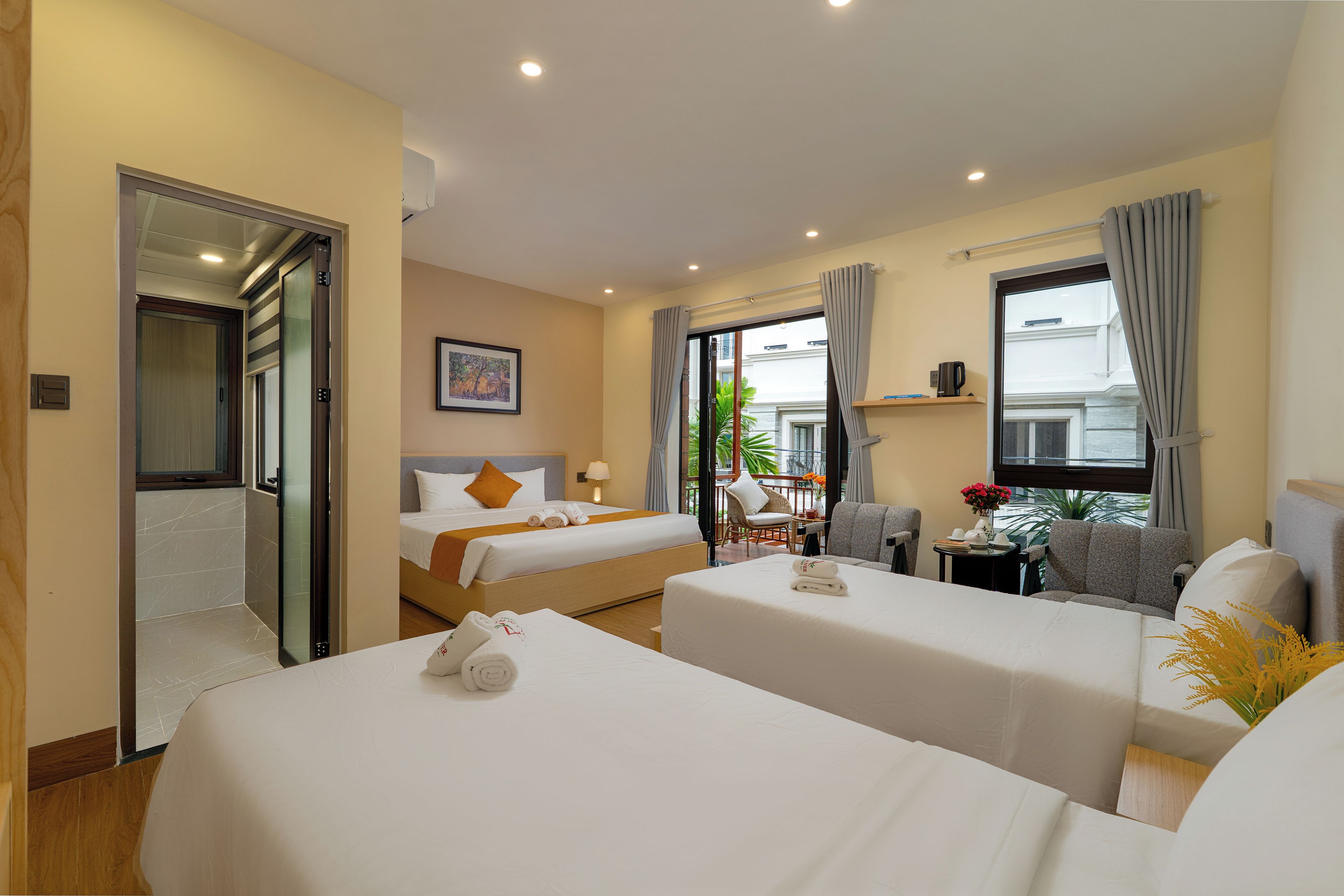 A hotel room with two beds, a sitting area, and a view of the outdoors.
