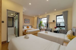 Una habitación de hotel con dos camas, un espacio para sentarse y vistas al exterior.