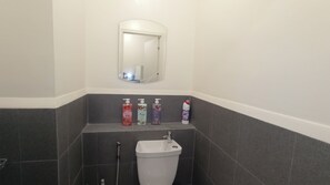 Un bagno con un lavandino bianco, uno specchio sopra e tre flaconi di sapone liquido su uno scaffale.