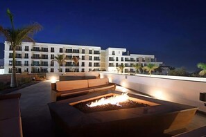 A rooftop terrace with a fire pit, outdoor seating, and a view of a multi-story hotel building. - Spacious 3-bedroom Penthouse,with a beautiful view in fabulous San José del Cabo (San José del Cabo)