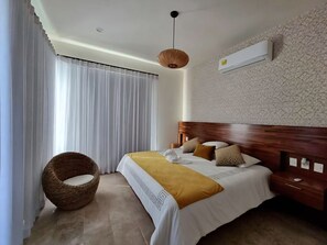 A bedroom with a bed, a wicker chair, a wooden headboard, and an air conditioning unit. - Spacious 3-bedroom Penthouse,with a beautiful view in fabulous San José del Cabo (San José del Cabo)