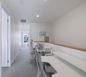 Catch up on emails or settle into a productive session at the dedicated workspace, where multiple desks and ergonomic chairs offer a practical setup away from the main living areas. - Wooloowin Escape Modern Comfort and Sunlit Courtyard (Brisbane)