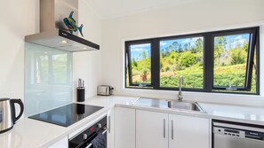 A modern kitchen with a large window, a toaster, and a kettle. - Road to Paradise | Mountain Views & Tranquility (Kopu)