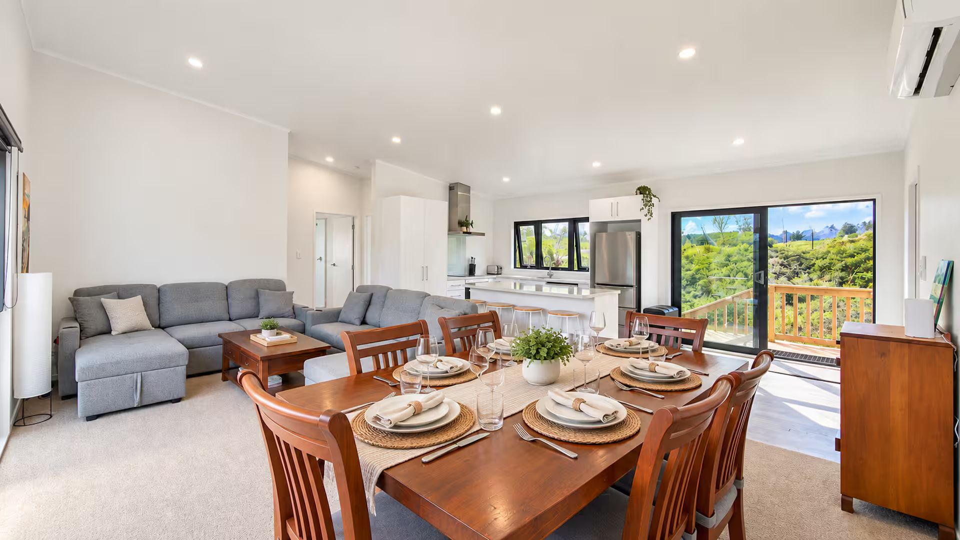 A modern living space with a dining area, kitchen, and a balcony with a scenic view.