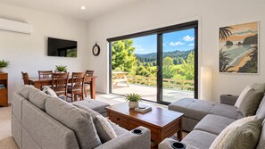 A modern living room with a sofa set, a wooden coffee table, and a dining area with chairs and a table.