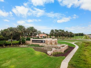 A landscaped area with a building labeled 'Sarasota National' and a paved walkway. - Relaxing pool home at Sarasota National Peace In The Palms (Venice)