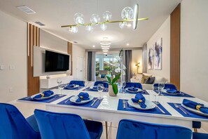 A modern dining room with a long table set for six, blue chairs, and a central vase with flowers. - 6BR Pool Home Near Disney at Windsor Island (Davenport)