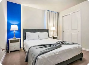 A neatly arranged bedroom with a bed, two bedside tables, and a door. - 6BR Pool Home Near Disney at Windsor Island (Davenport)