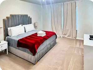A modern bedroom with a bed, nightstand, and a desk. - 5BR Disney-Themed Getaway with Pool (Davenport)