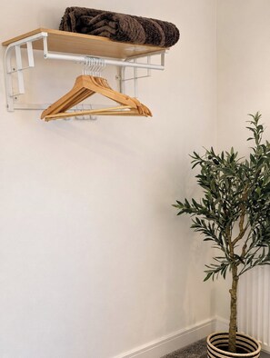 A wall-mounted wooden shelf with a folded blanket and a wooden hanger. - Spacious 5BR Durham Home | Ideal for Contractors (Bearpark)
