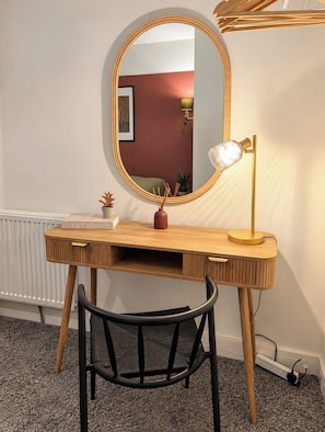 A wooden desk with a round mirror, a lamp, and a chair in a room with a radiator and a wall with a picture. - Spacious 5BR Durham Home | Ideal for Contractors (Bearpark)