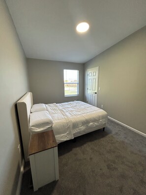 Un dormitorio con una cama, una ventana y una puerta.
