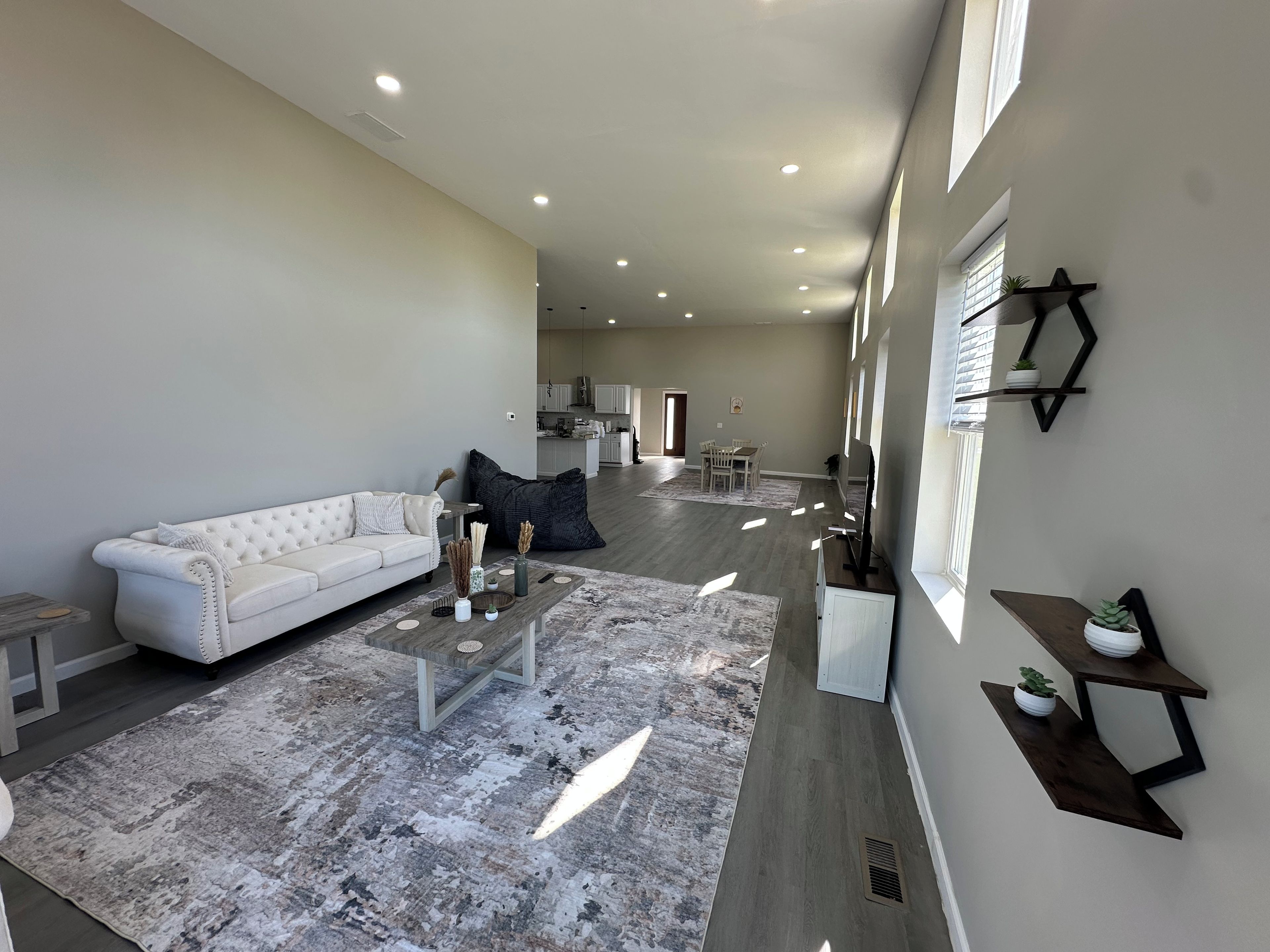 A spacious living room with a white sofa, a coffee table, and a large rug.
