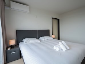 Ein Hotelzimmer mit Bett, Nachttisch, Lampe und Klimaanlage.