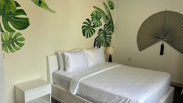 A bed with white bedding, a bedside table, a lamp, and a wall-mounted fan.