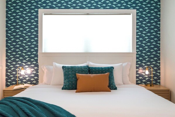 Habitación de hotel con una cama grande, dos lámparas de noche y un ventanal con vistas.