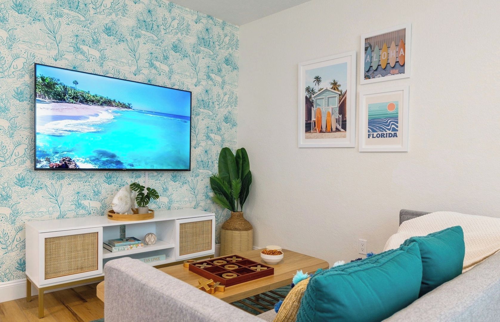 A living room with a flat-screen TV, a coffee table, a sofa, and wall art.