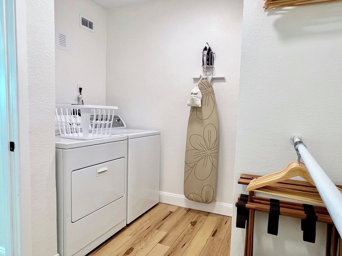 A laundry area with a washing machine, drying rack, and iron.