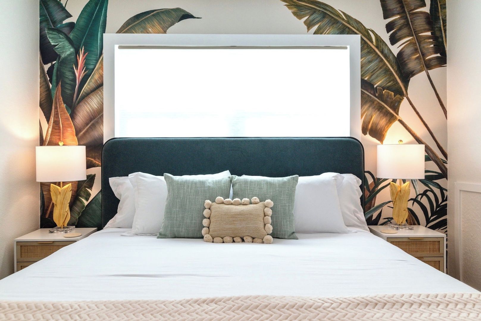 A bed with a white headboard, multiple pillows, and two bedside lamps.