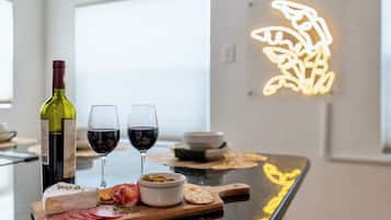 Una zona de bar con una botella de vino, dos copas de vino tinto, una tabla de quesos y un bol de aceitunas.