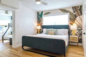 Un dormitorio con cama, lámparas de noche, un mural en la pared y una escalera.