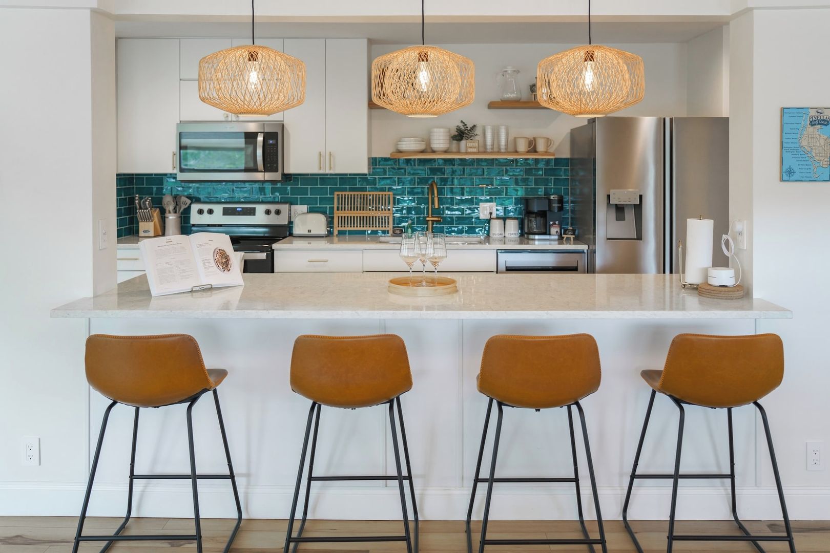 A modern kitchen with a central island, stainless steel appliances, and a teal backsplash.