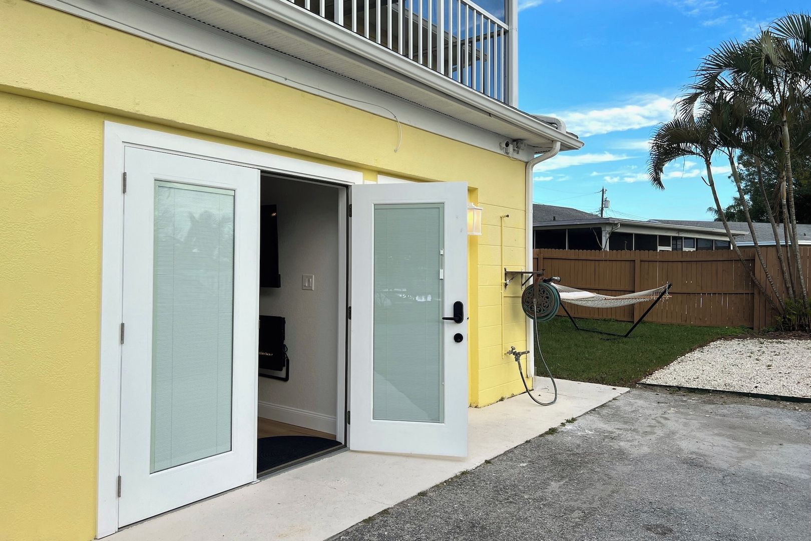 Un bâtiment jaune avec une porte blanche et un petit porche fermé.